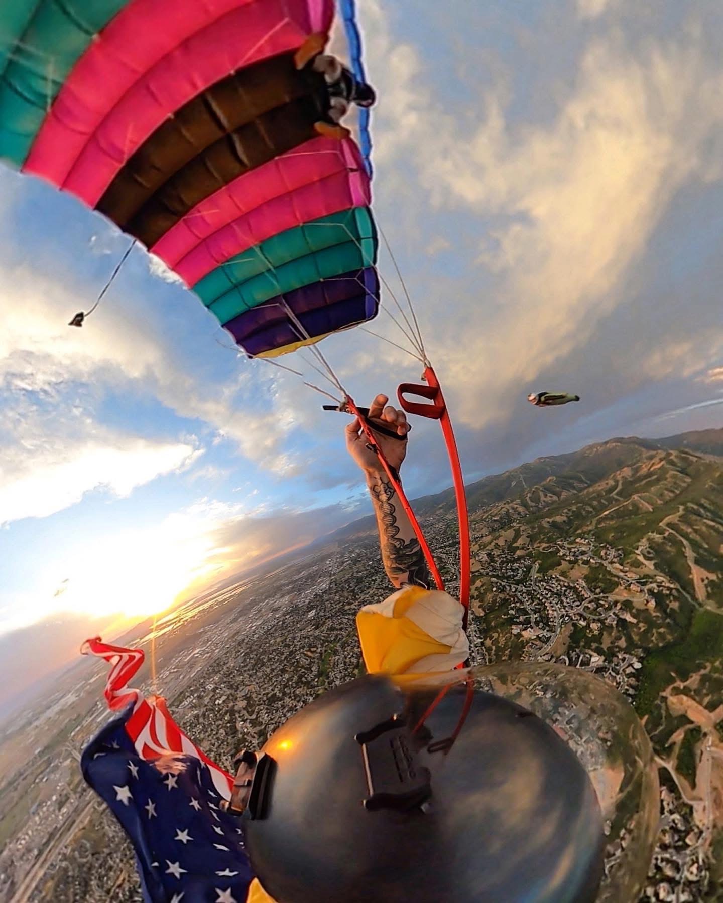 A colorful parachute above the mountains and city at sunset